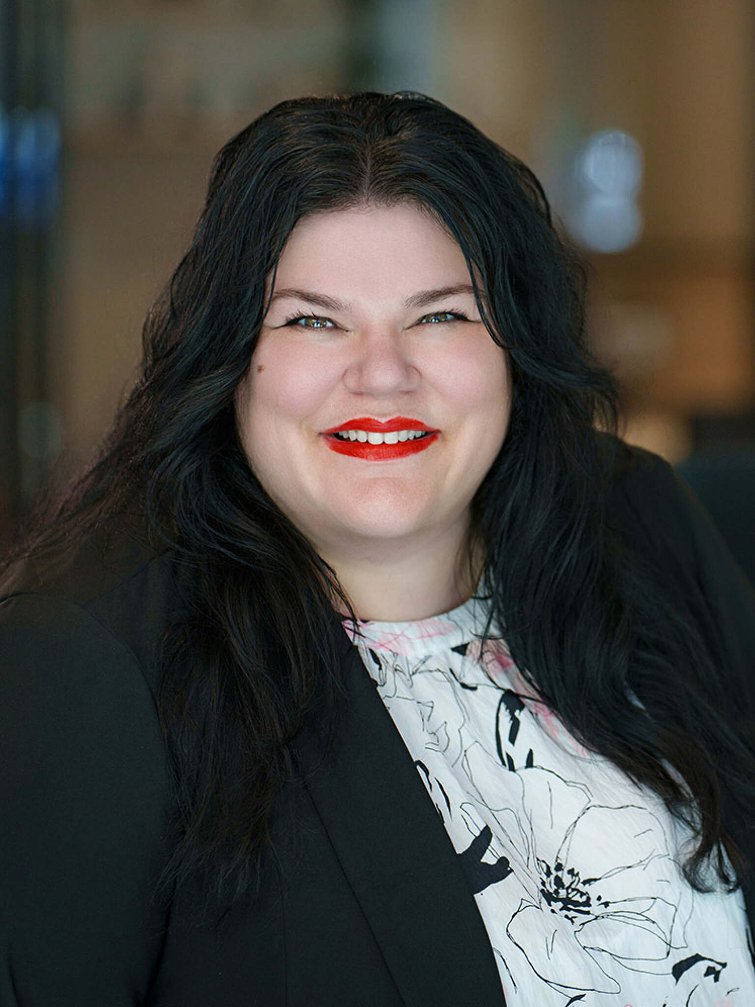 woman with black hair and red lipstick smiling for a headshot