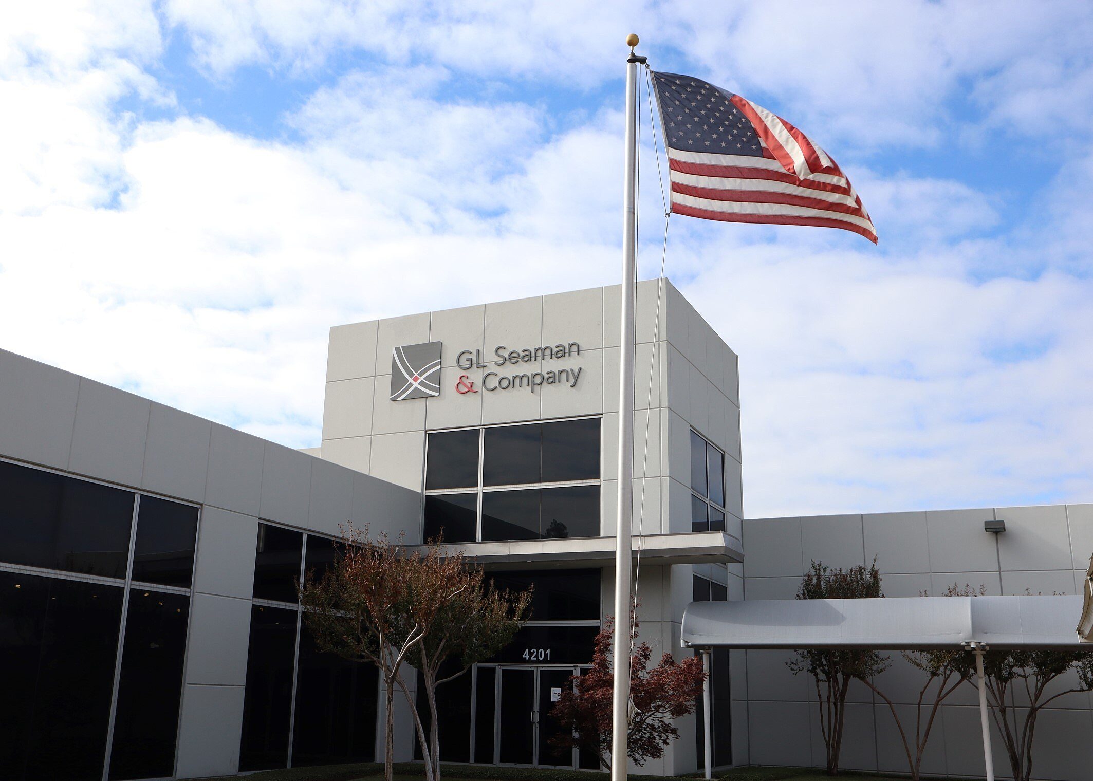 outside of GL Seaman & Company Dallas Headquarters with an American flag on a flag pole and a white exterior