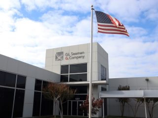 outside of GL Seaman & Company Dallas Headquarters with an American flag on a flag pole and a white exterior