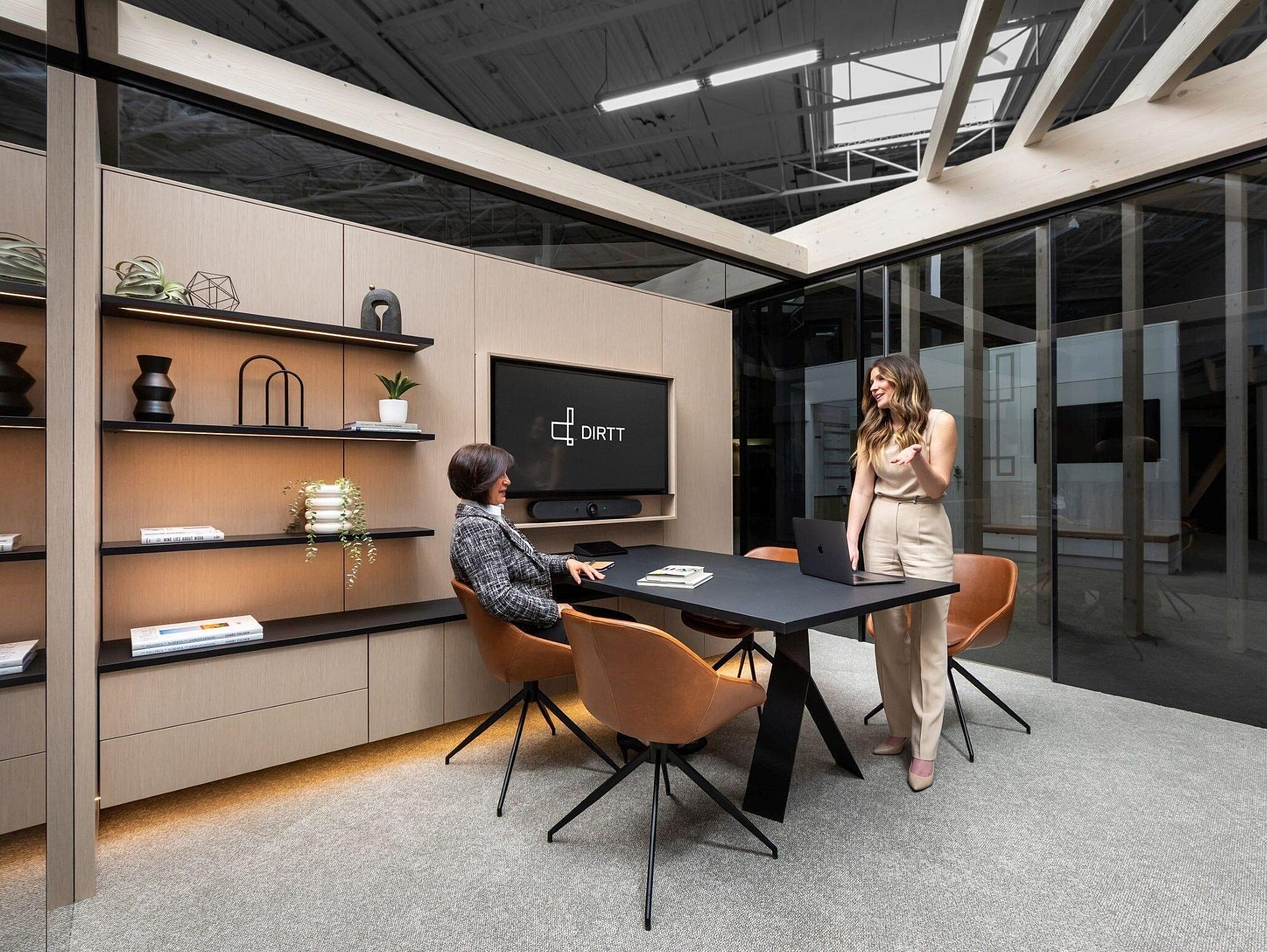 DIRTT private office space with shelves, a table, chairs, and a TV integrated into the wall