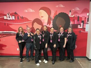 a group of people standing in front of a mural at the National Breast Cancer Foundation