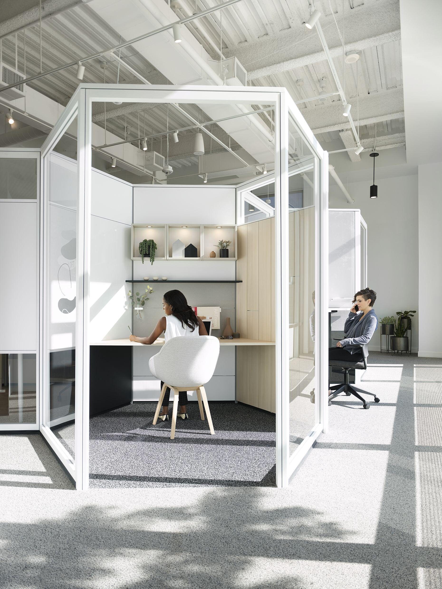 Work pods for employees that are enclosed with glass and have a desk and chair