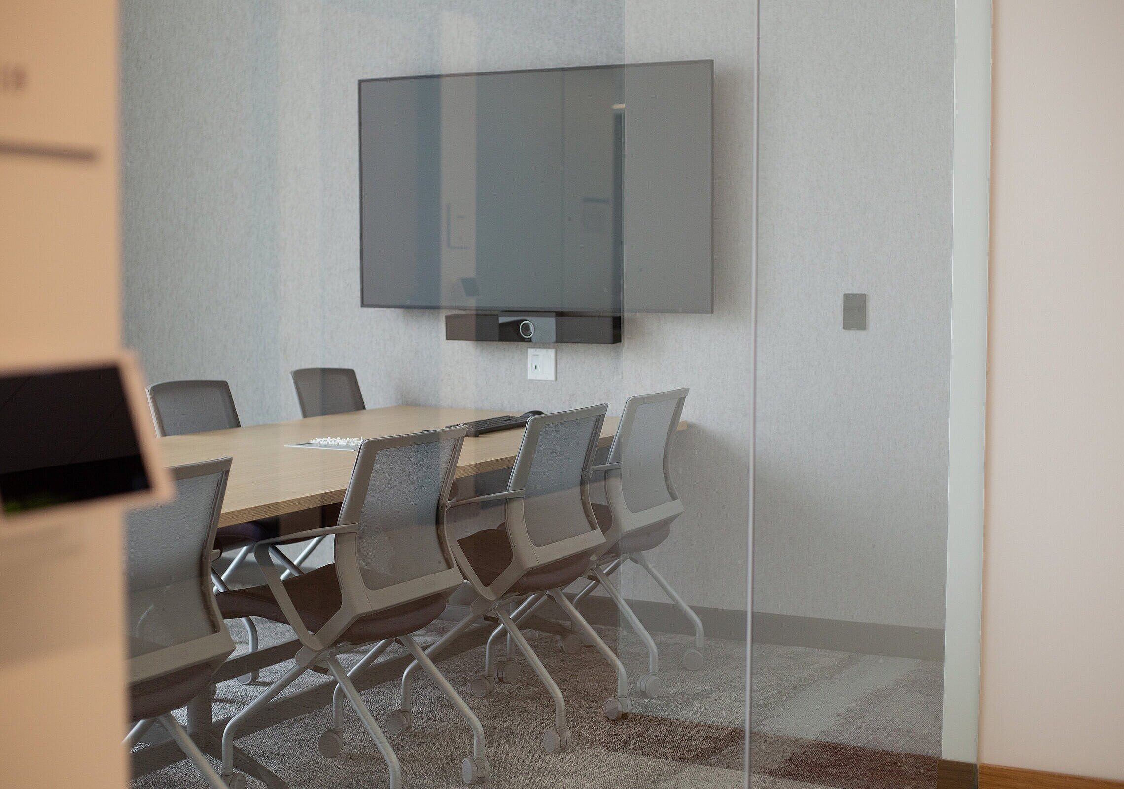 TCU Burnett School of Medicine small conference room with a large rectangular table and 8 task chairs and a tv