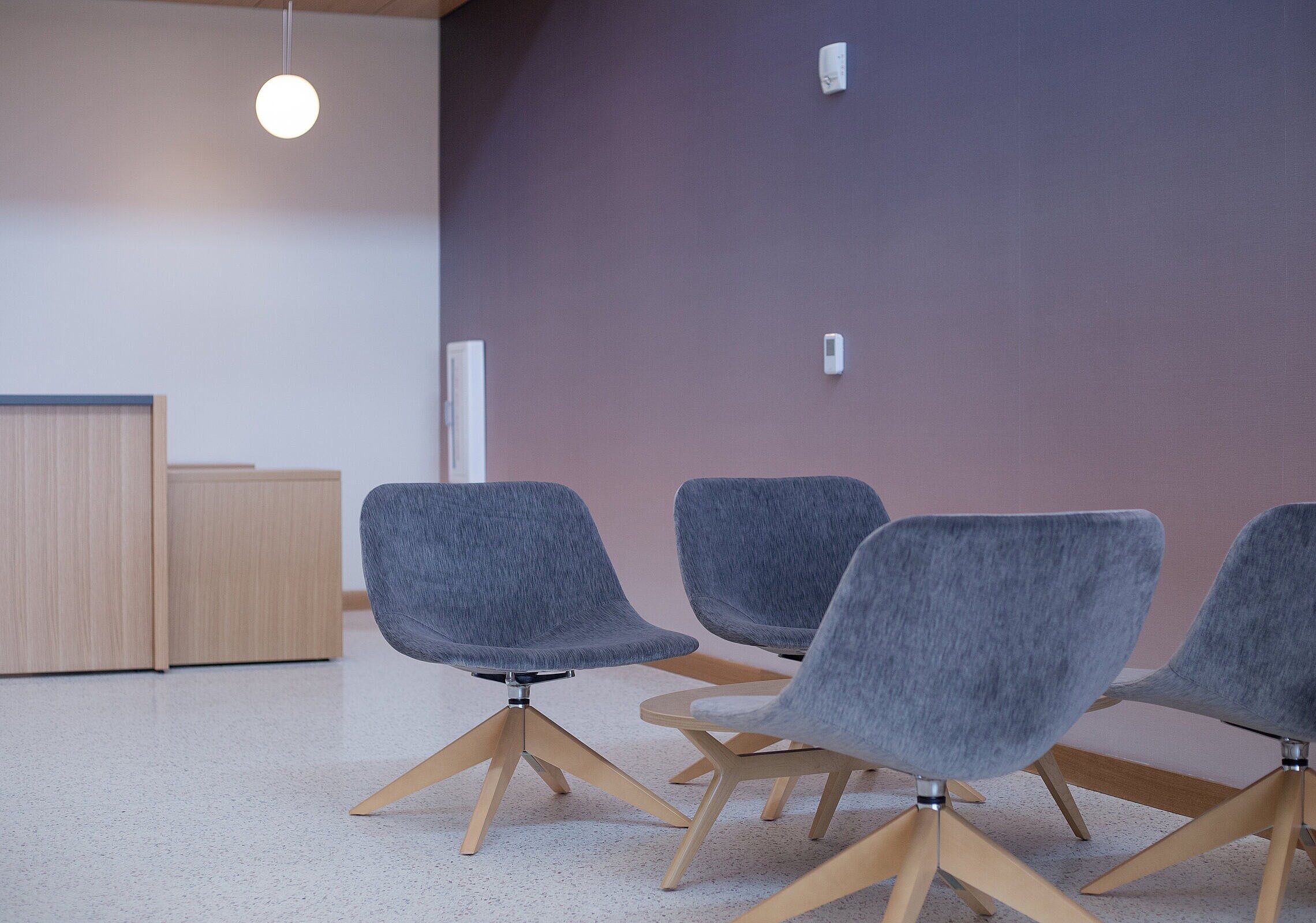 TCU Burnett School of Medicine Lounge Seating and Reception with 4 lounge chairs around a round wooden coffee table and a wooden reception desk is left