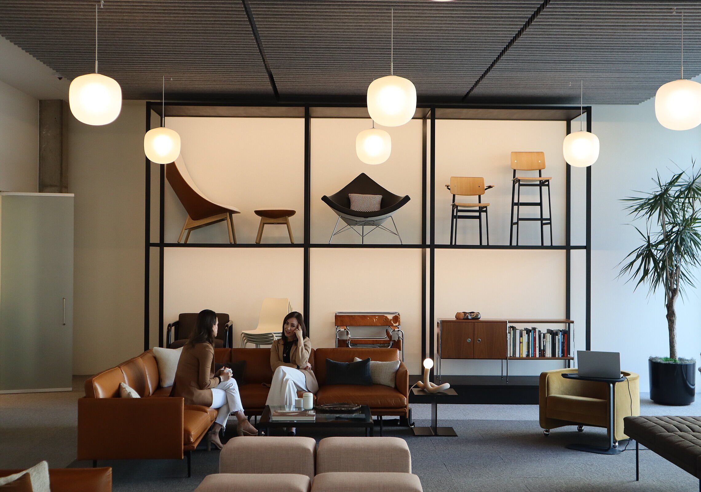 Coworkers sitting and chatting on a Muuto couch in the MillerKnoll Showroom in Dallas, TX