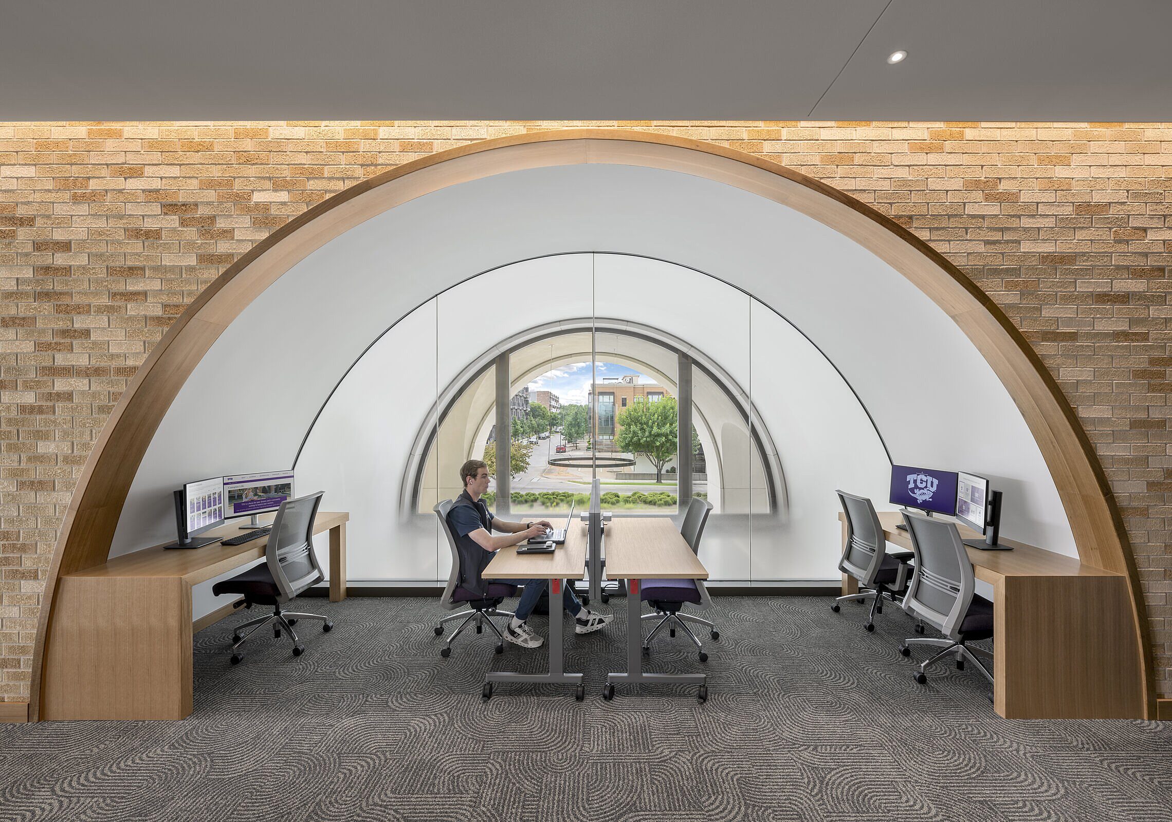 Student working at a table underneath an archway in a study space at TCU Burnett School of Medicine