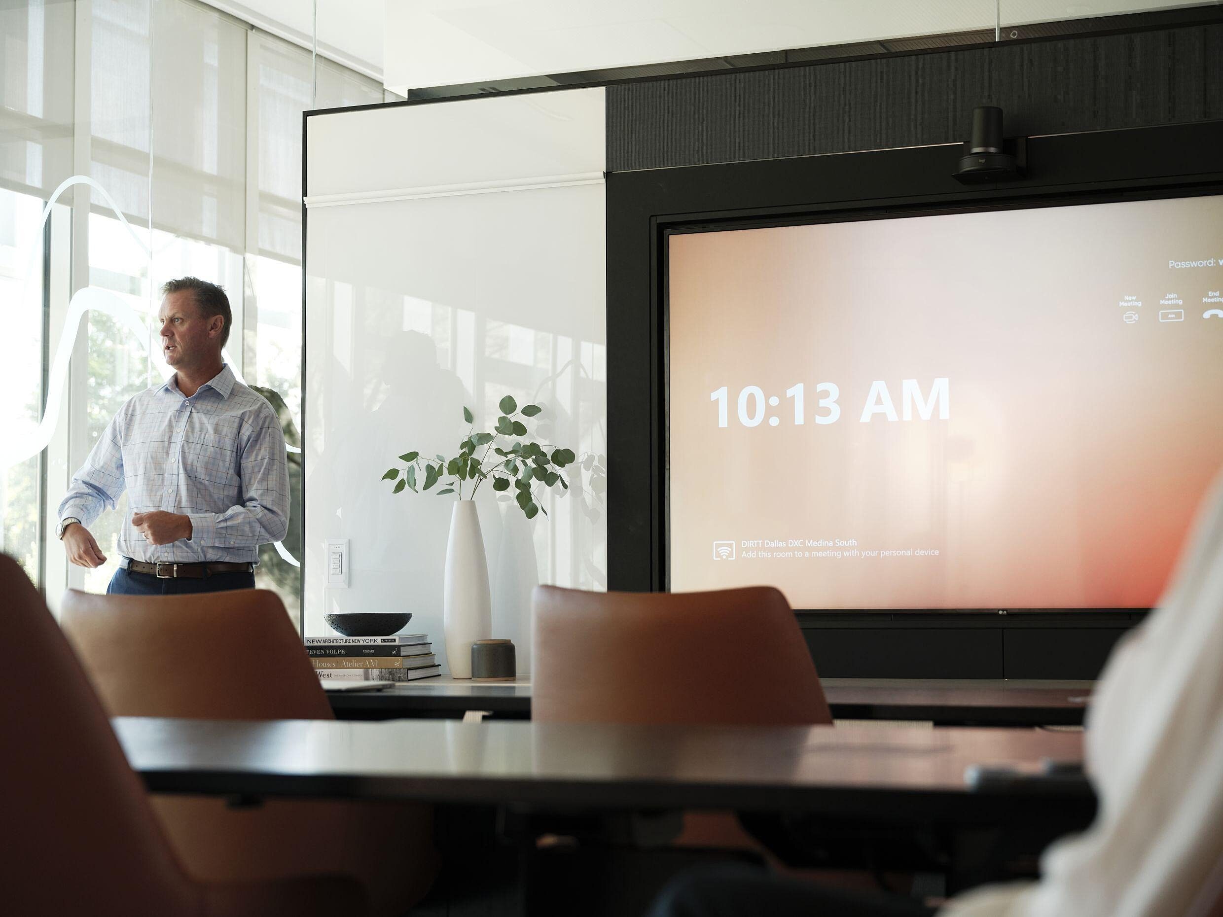 Man leading a meeting in a conference room using integrated technology screens