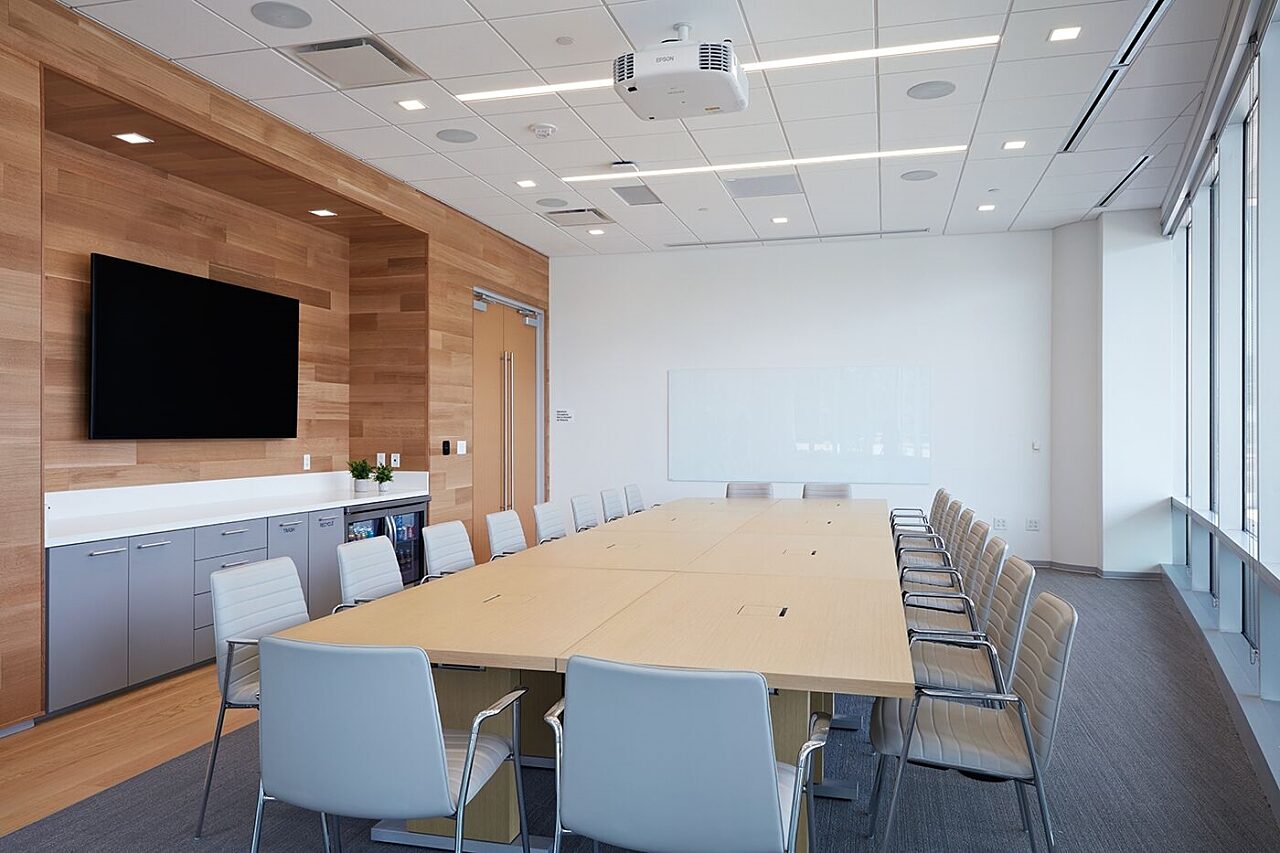 corporate conference room with a large conference table, chairs, and a tv screen