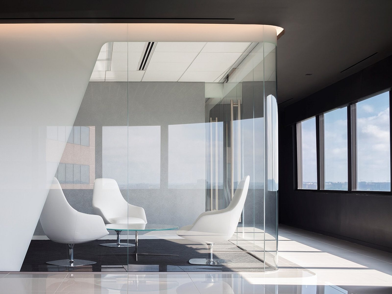 Corporate office small conference room with, chairs, and a coffee table all enclosed in glass walls