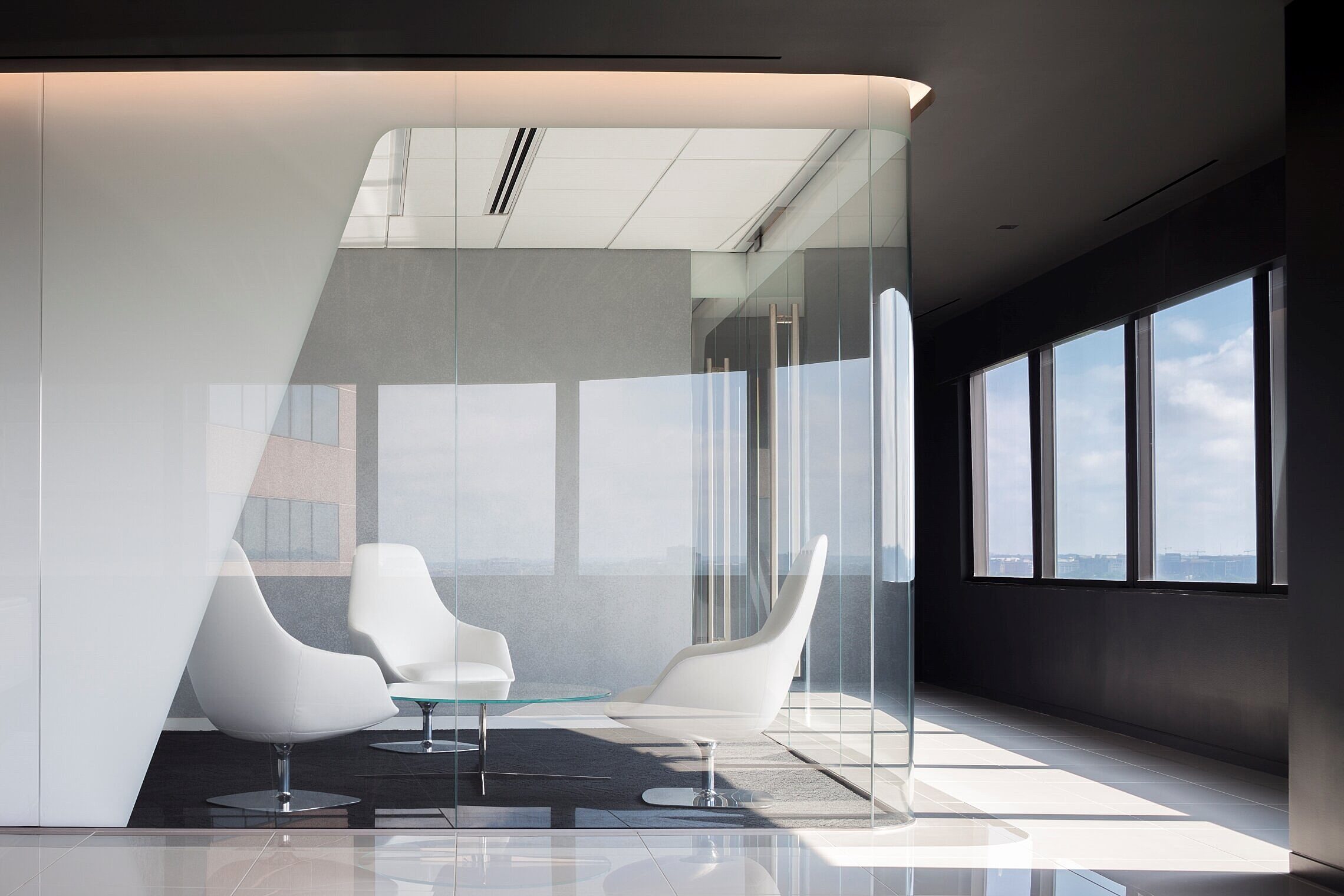 Corporate office small conference room with, chairs, and a coffee table all enclosed in glass walls