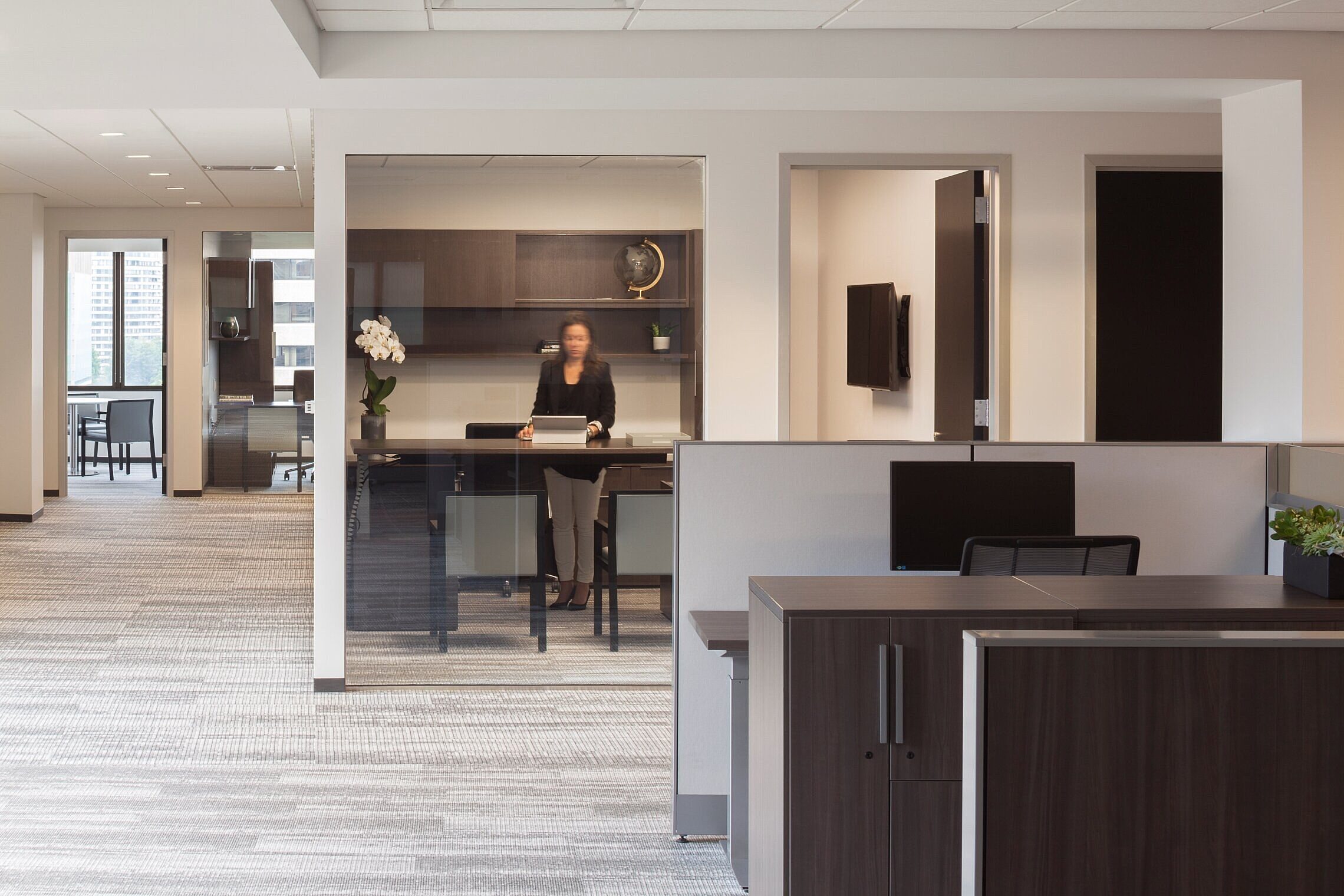 corporate office workstation with monitor and chair, and a small private office
