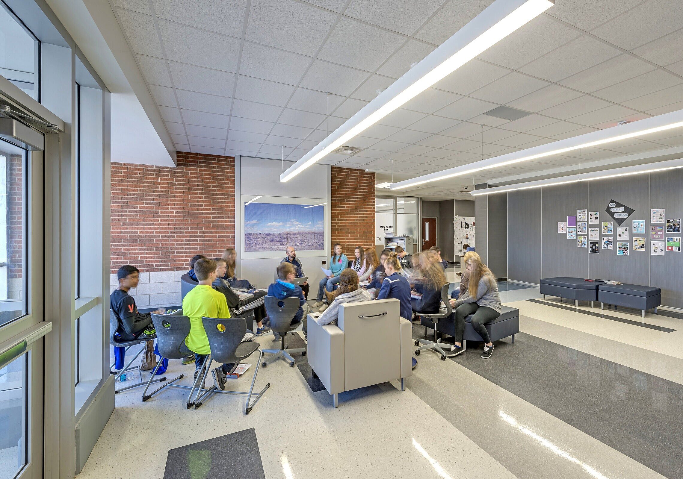 DIRTT Education embedded technology wall with a group of students sitting in chairs surrounding their teacher ready to learn