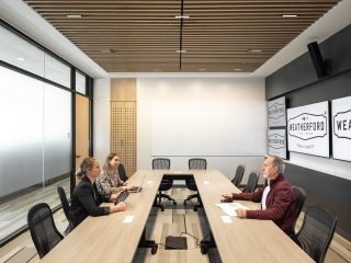 City of Weatherford Public Safety Building Meeting Room with a large rectangular wooden conference room, black ergonomic chairs, and 3 people sitting