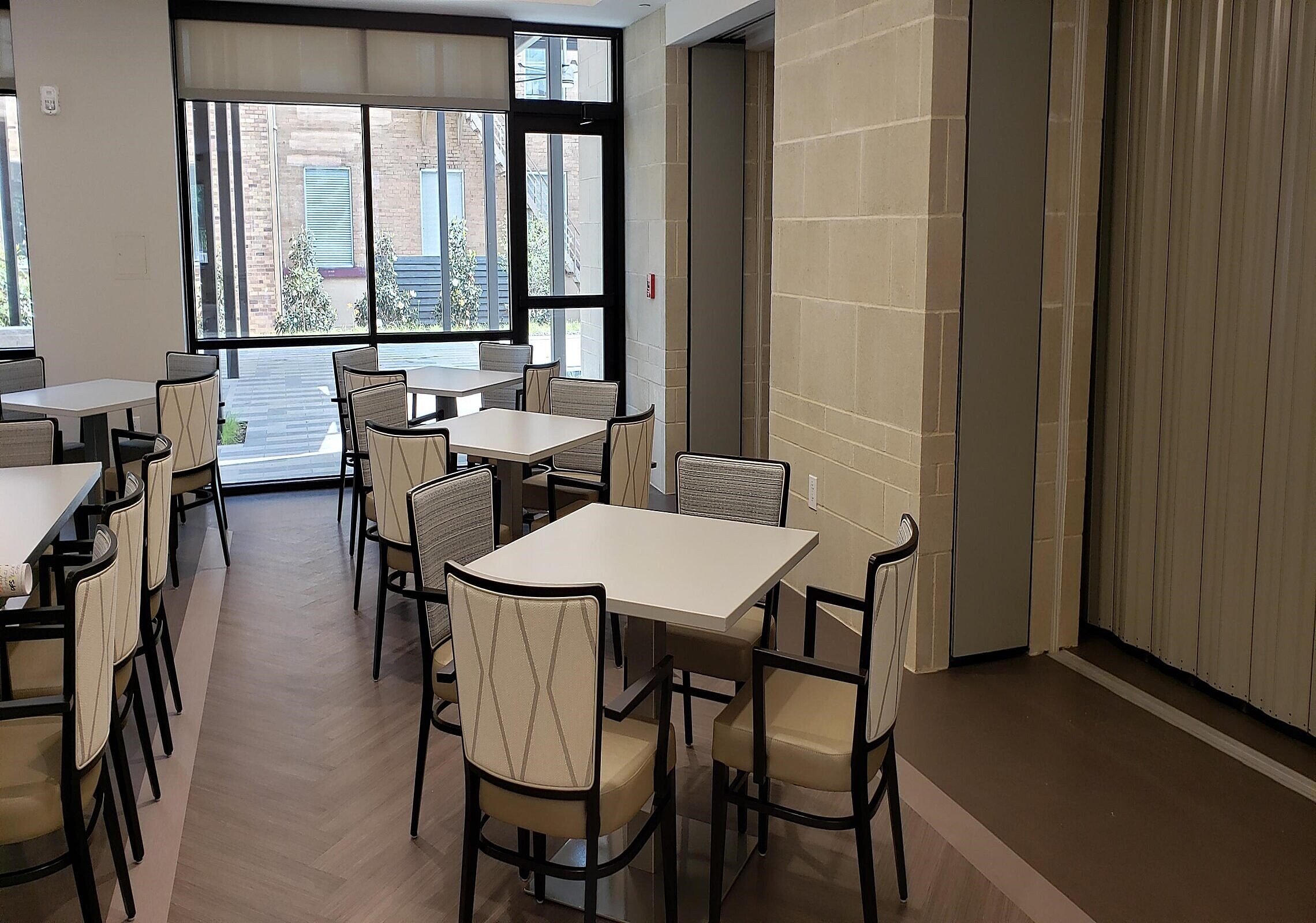Texas Masonic Retirement Center in Arlington dining space with square white tables surrounded by 4 cream and black chairs